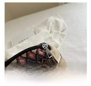 Close-up of smooth metal zipper and woven geometric jacquard fabric on bohemian crossbody bag