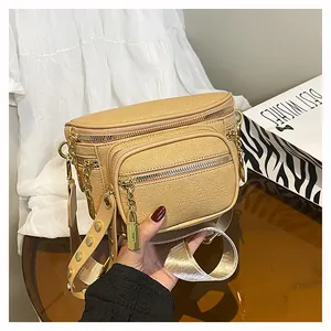 Dettaglio borsa a tracolla beige con trama litchi e rivetti dorati sulla tracolla