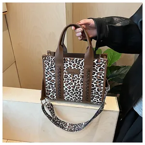 Nahaufnahme der Leopardenmuster-Tasche mit Marken-Logo und breitem Schultergurt