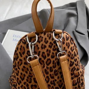 Detailed view of silver metal hooks and brown leather straps on a leopard print backpack