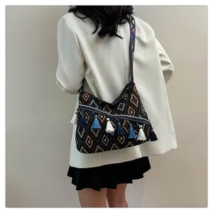 Dettaglio borsa etnica con motivi geometrici, frange blu e tracolla in tessuto jacquard