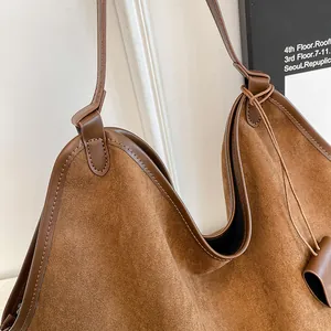 Gros plan du sac cabas en daim marron caramel avec surpiqûres et finitions en cuir