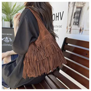 Dettaglio di una borsa a tracolla scamosciata marrone con frange lunghe e stile boho