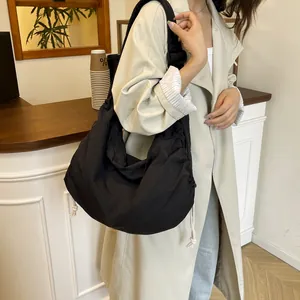Large black nylon crossbody dumpling bag with drawstring details and wide shoulder strap