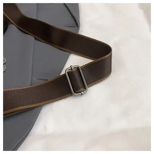 Dettaglio della tracolla in nylon intrecciato marrone con fibbia in metallo regolabile
