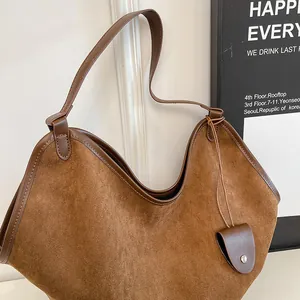 Détail du cabas en daim marron avec bords en cuir renforcés et porte-cartes suspendu
