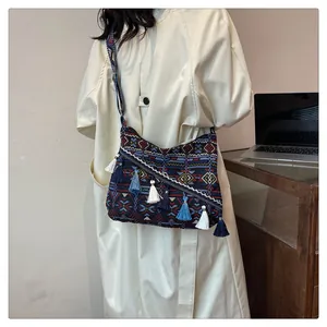 Dettaglio della borsa etnica in tessuto con nappe colorate e motivi geometrici boho