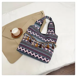 Dettaglio della borsa tote boho tessuta con motivi geometrici e ciondolo a nappa