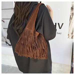 Dettaglio di una borsa a spalla in camoscio marrone con frange lunghe stile boho
