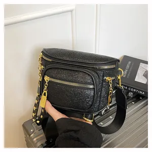 Dettaglio della borsa pettorale nera in tessuto testurizzato con zip e rivetti dorati