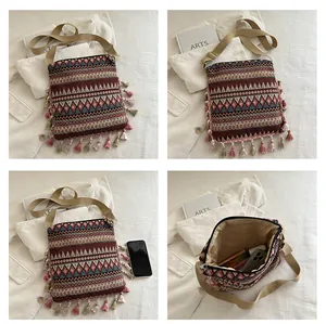 Detail view of ethnic geometric jacquard fabric with colorful tassel trim on crossbody bag