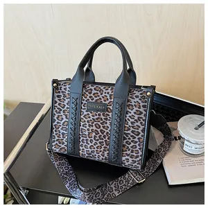 Detailansicht der Handtasche mit Leopardenmuster, schwarzen Lederkanten und Webdekor