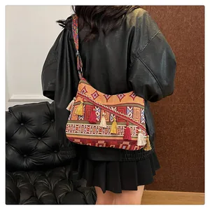 Dettaglio della borsa hobo jacquard etnica con frange a nappa e tracolla larga tessuta
