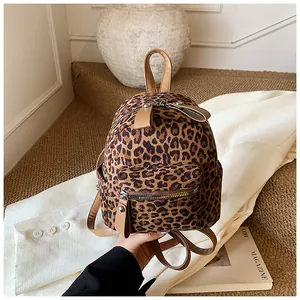 Detailed view of mini leopard print backpack on a beige blazer with brown leather straps