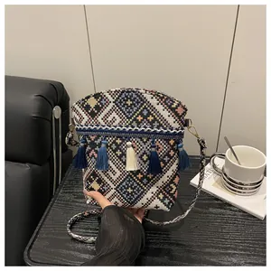 Dettaglio della borsa a secchiello etnica con motivi geometrici e nappe blu