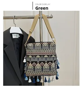 Detail of green bohemian crossbody bag with geometric jacquard and fringe accents