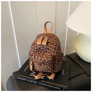 Close-up of leopard print mini backpack with brown faux leather trim on a design book