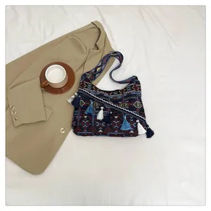 Dettaglio borsa boho in tessuto con motivi etnici e nappine colorate