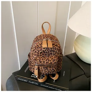 Detailed view of mini leopard print backpack with tan leather trim on design books