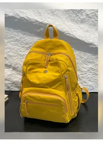 Dettaglio dello zaino in nylon giallo che mostra la trama impermeabile e il design multitasche
