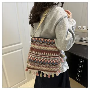 Detail of geometric jacquard crossbody bag with colorful bohemian fringe and strap