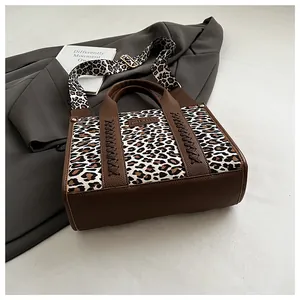 Detailansicht der Leopard-Tragetasche mit gewebtem Ledergriff und breitem Schultergurt