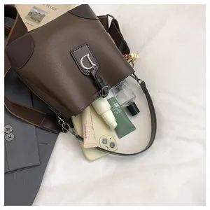 Dettaglio della borsa a secchiello marrone con fibbia argento e capacità di carico interna