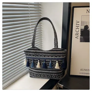 Dettaglio dei motivi jacquard e nappe blu su una borsa a tracolla in tessuto etnico