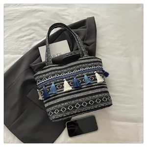 Dettaglio della borsa tote jacquard bohémien con motivi geometrici e nappe blu decorative