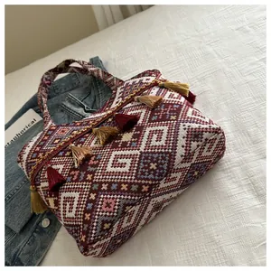 Dettaglio borsa tote in tessuto con motivi etnici geometrici e ciondoli con nappe colorate