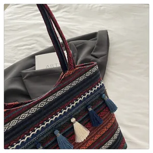 Dettaglio borsa tote jacquard boho con strisce geometriche e nappe blu pendenti