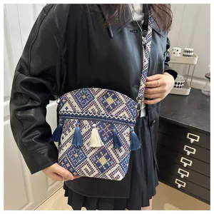 Dettaglio borsa a secchiello boho intrecciata con nappe e tracolla a motivi geometrici