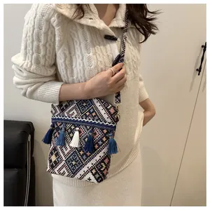 Dettaglio della borsa a secchiello boho con motivi jacquard e nappine con frange blu
