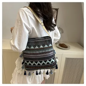 Close-up of geometric woven patterns and vibrant colorful fringe on a bohemian crossbody bag
