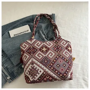 Dettaglio della borsa tote etnica intrecciata con ricami geometrici e nappe alla moda