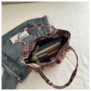 Dettaglio interno di borsa tote etnica intrecciata con grande capacità e nappe decorative