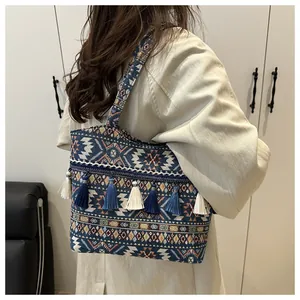 Dettaglio ravvicinato della borsa tote etnica intrecciata con motivi geometrici e nappe