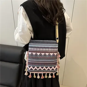Bohemian geometric crossbody bag with tassels shown on a model in a minimalist room