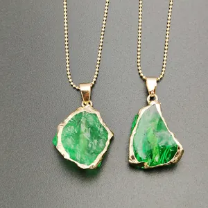 Detailed macro of gold plated irregular green crystal pendants with beaded ball chains