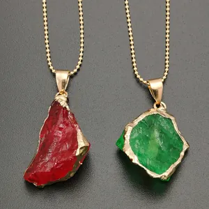 Macro shot of irregular red and green crystal pendants with gold plated edges on ball chains