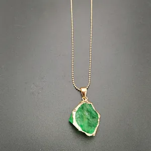 Detail of raw green crystal pendant with gold-plated brass edge on a golden bead chain