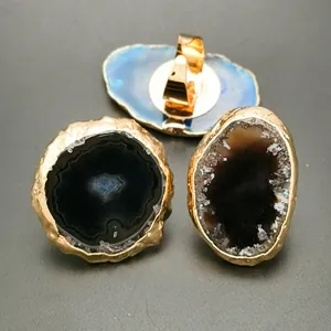 Natural agate stone rings with irregular gold plated edges on a black textured background