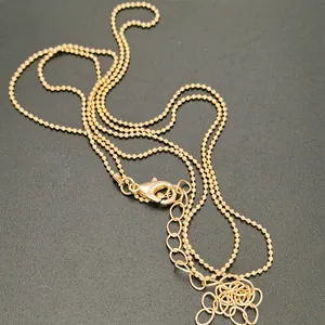 Close-up of golden beaded necklace chain with lobster clasp and extension details
