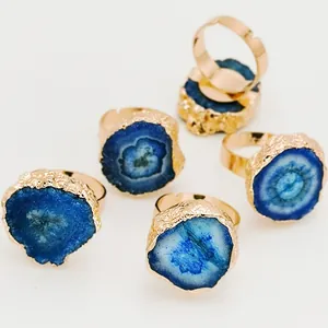 Détail de cinq bagues dorées ajustables avec tranches d'agate bleue naturelle en tournesol