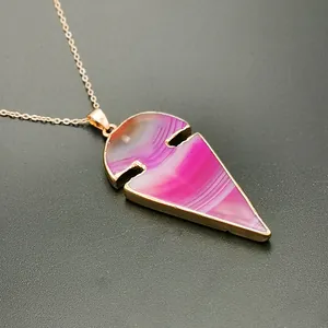 Detalle macro del colgante de ágata rosa en forma de flecha con borde de metal dorado