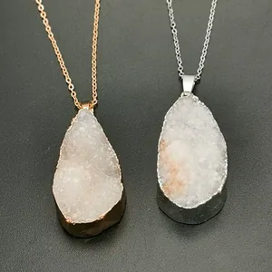 Detailansicht der silbernen und roségoldenen Druzy-Kristallketten auf grauem Grund