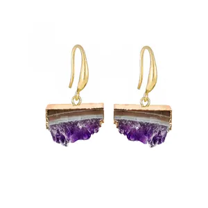 Détail de boucles d'oreilles en grappe d'améthyste brute avec bordure et crochets dorés