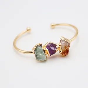 Brazalete dorado abierto con tres piedras naturales en verde, morado y color ámbar