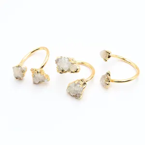 Détail de trois bagues dorées avec pierres naturelles de druzy en cristal blanc brut