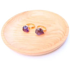 Natural amethyst raw stones in gold plated adjustable open rings on a wooden tray